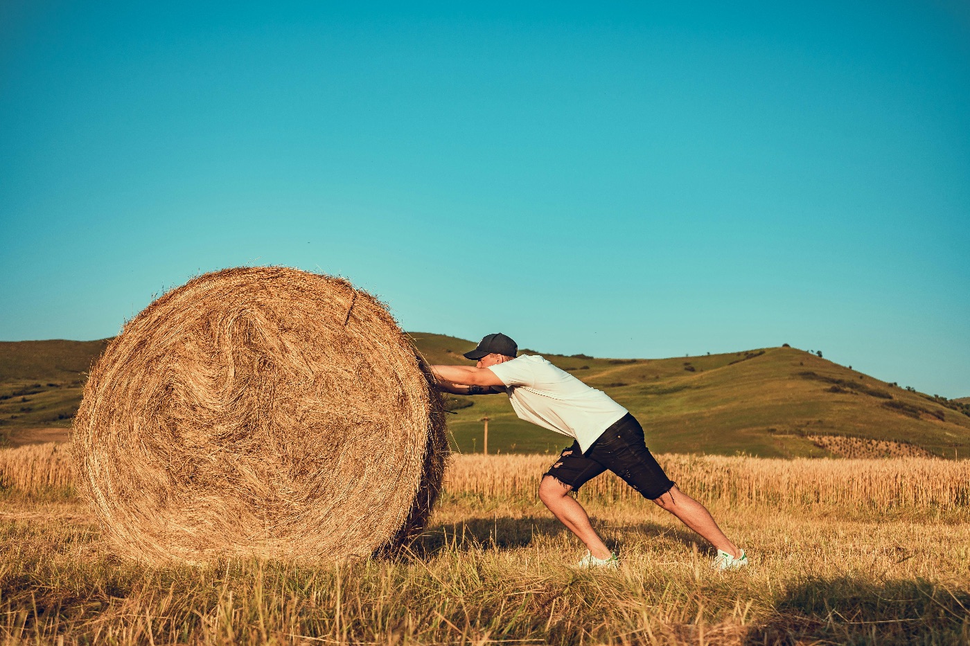 Man, pushing a haystack. 