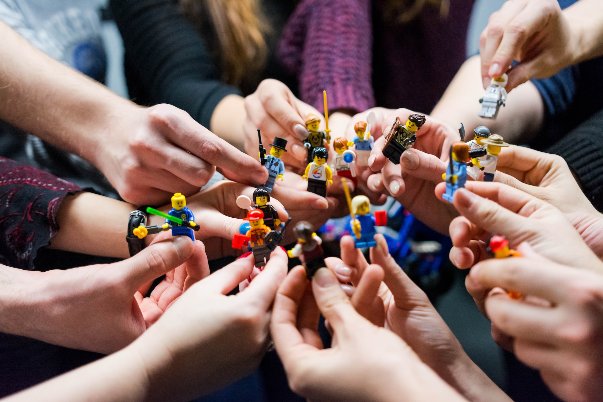 Team of people, holding lego figs together