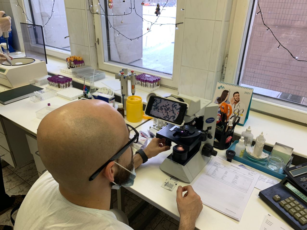 A physician examines a blood smear under the microscope via the iPhone.