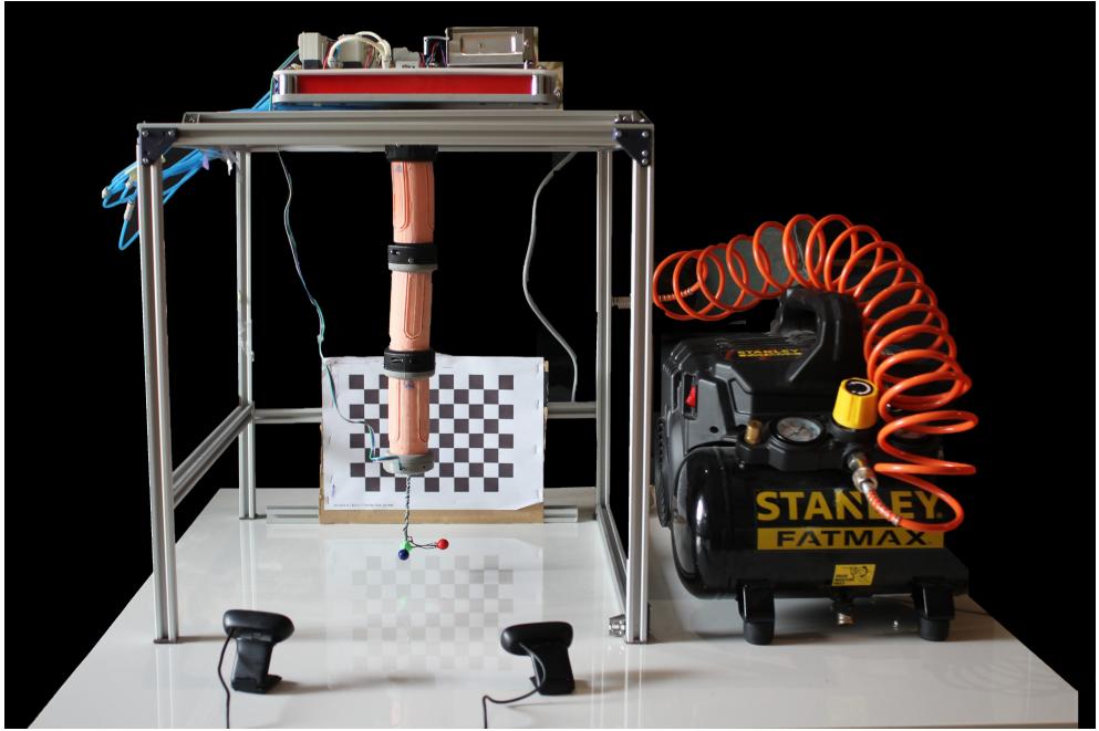 Figure 1. PAUL robot. The figure shows the arm, with its three segments and the trihedron that allows its position and orientation to be known, as well as the pneumatic actuation bench (at the top), the compressor (on the right) and the two cameras and the calibration grid, which make up the vision system. Source: authors.