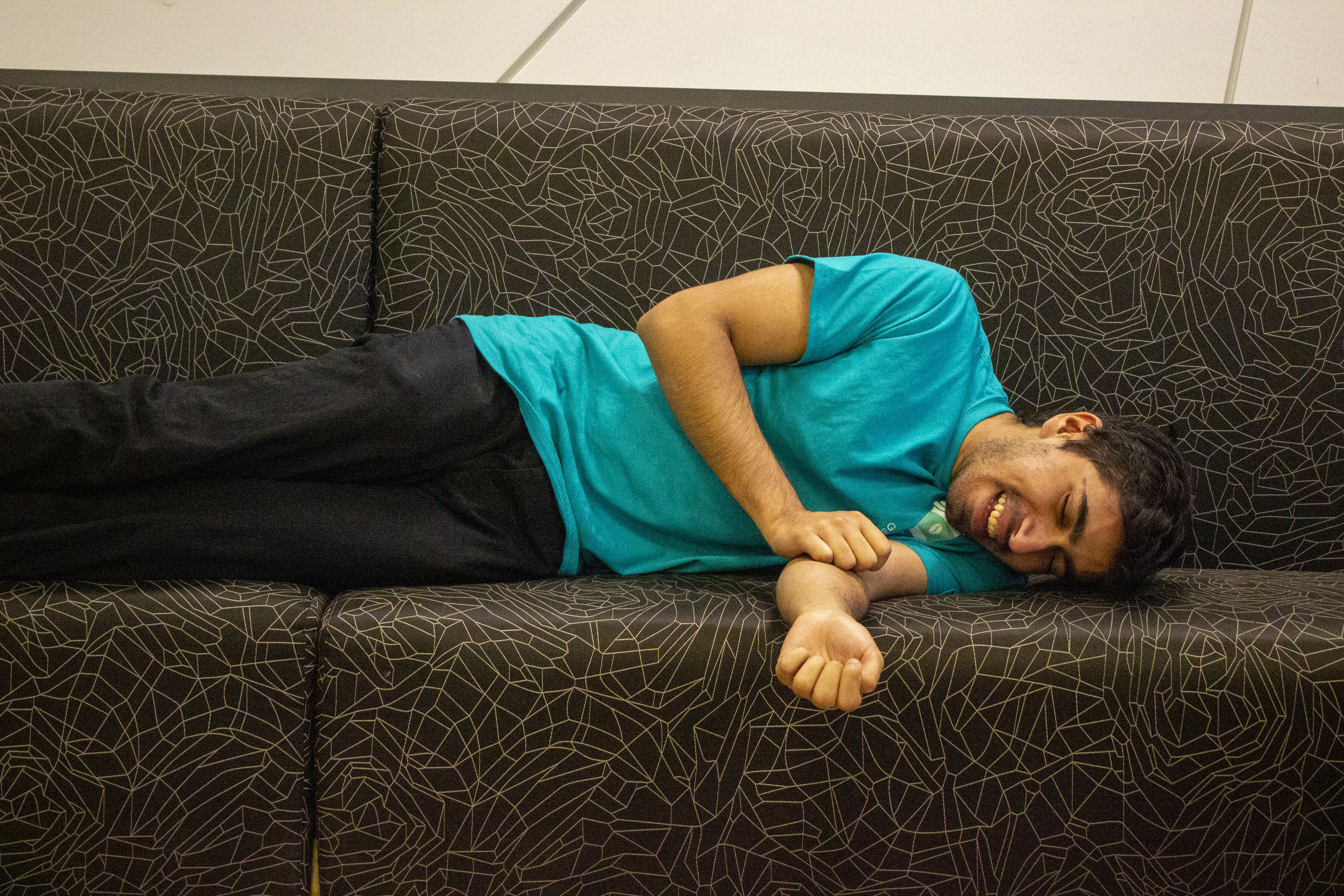 Daniyal laughing on a couch in their office space located at York University.