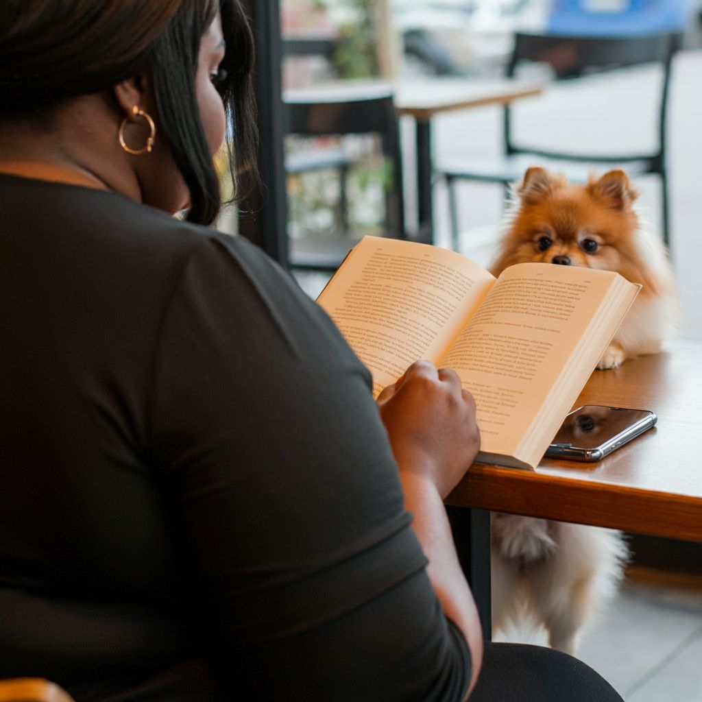 Over-the-shoulder shot of a a Nigerian woman sitting in a coffee shop with a Pomeranian